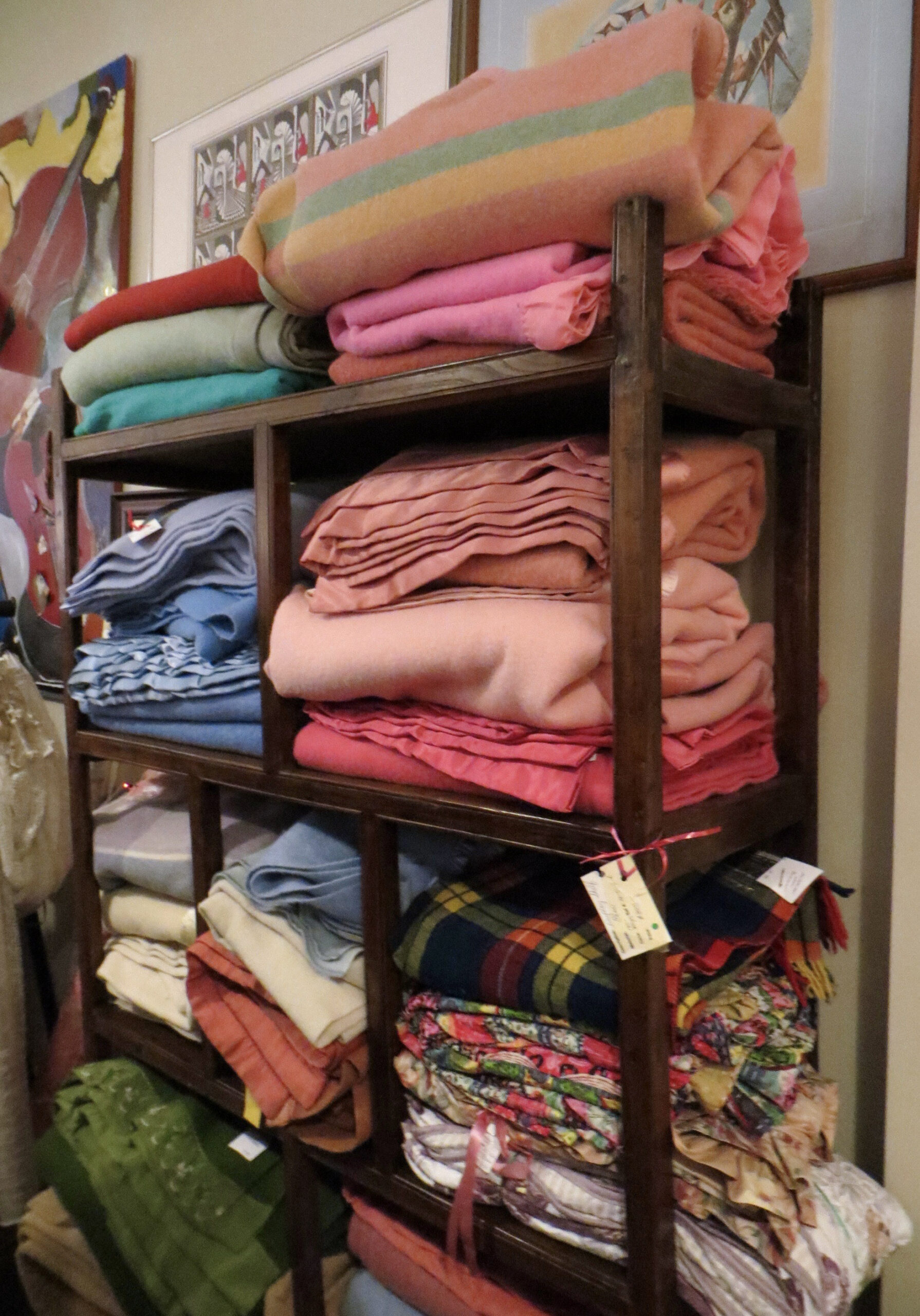 Wooden shelving holds an assortment of folded, colourful blankets.