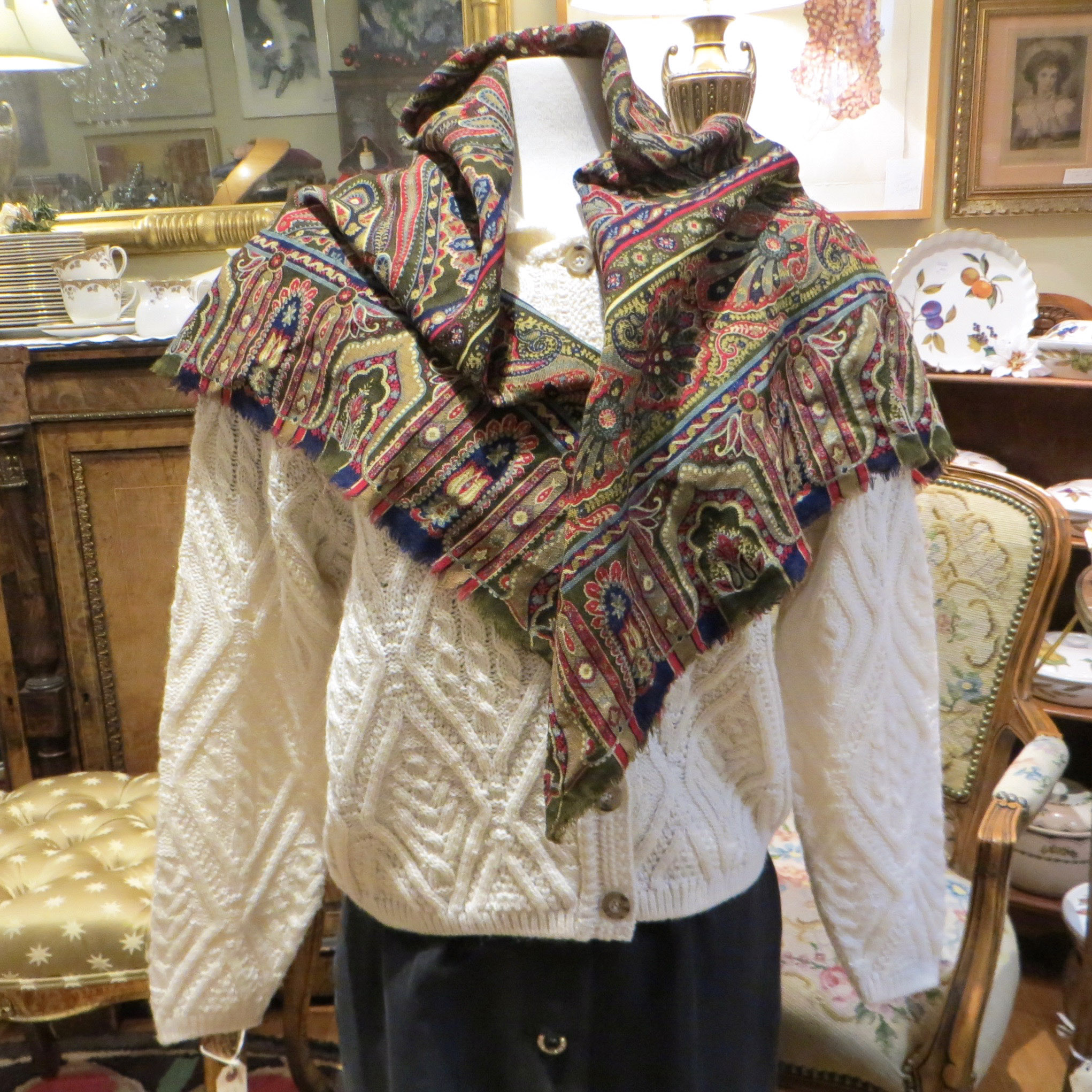 A cotton paisley shawl is draped over a mannequin wearing a white wool sweater.