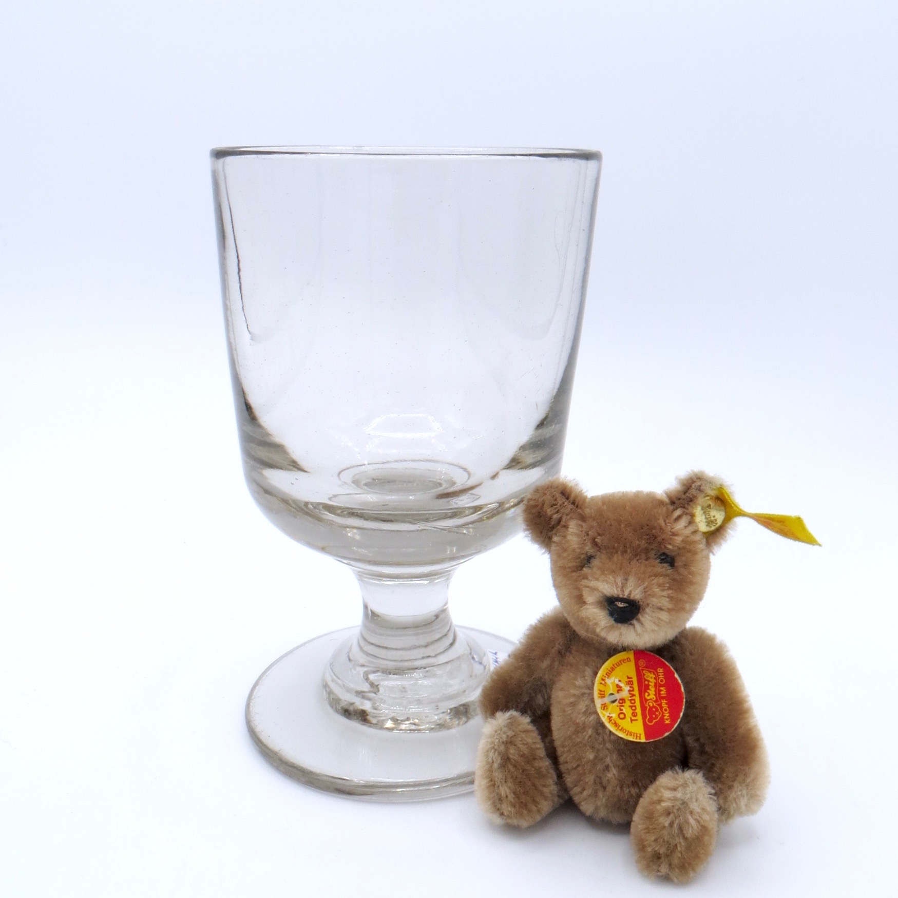 A large glass on the left, and a small teddy bear on the right for scale.