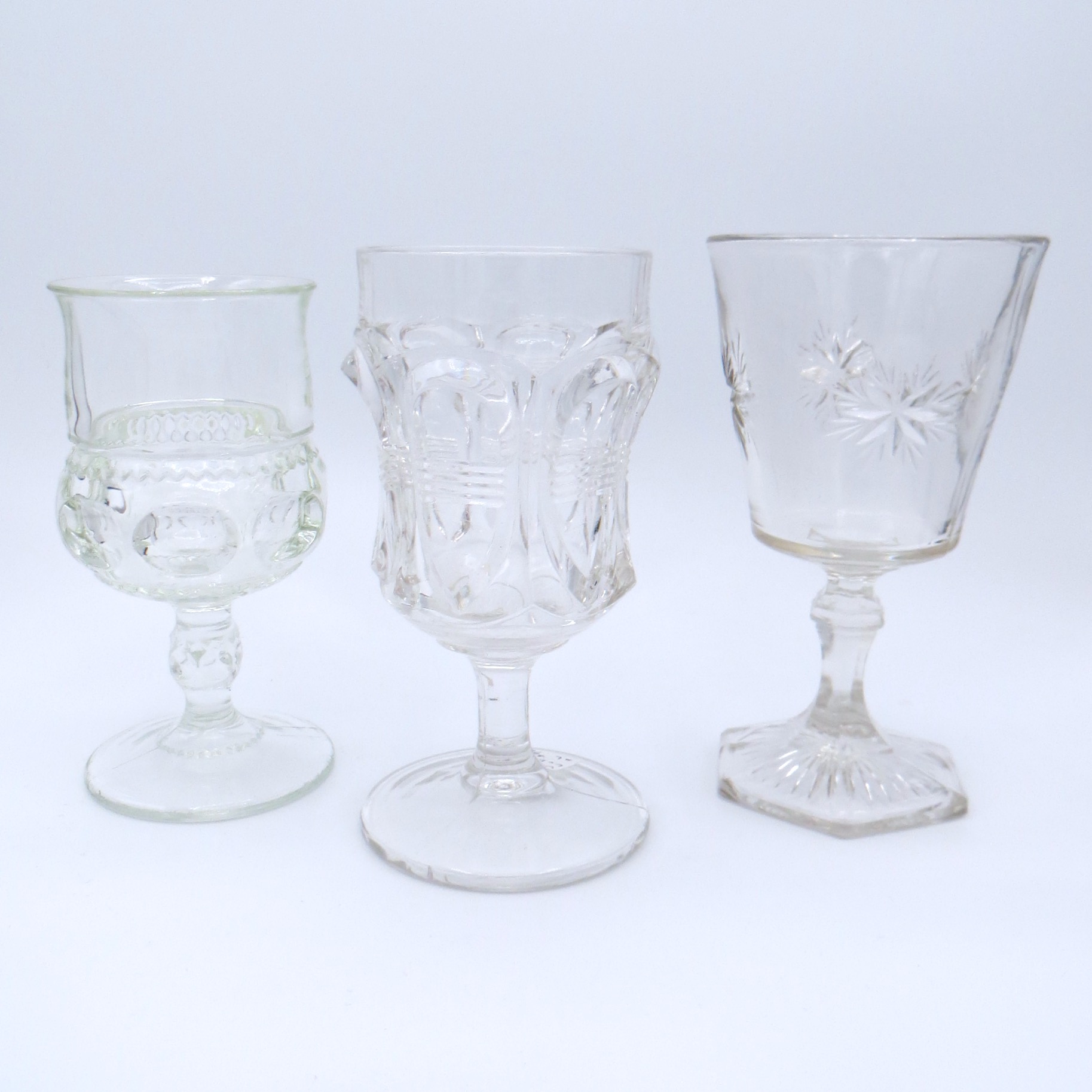 Three cut glass goblets with different patterns.